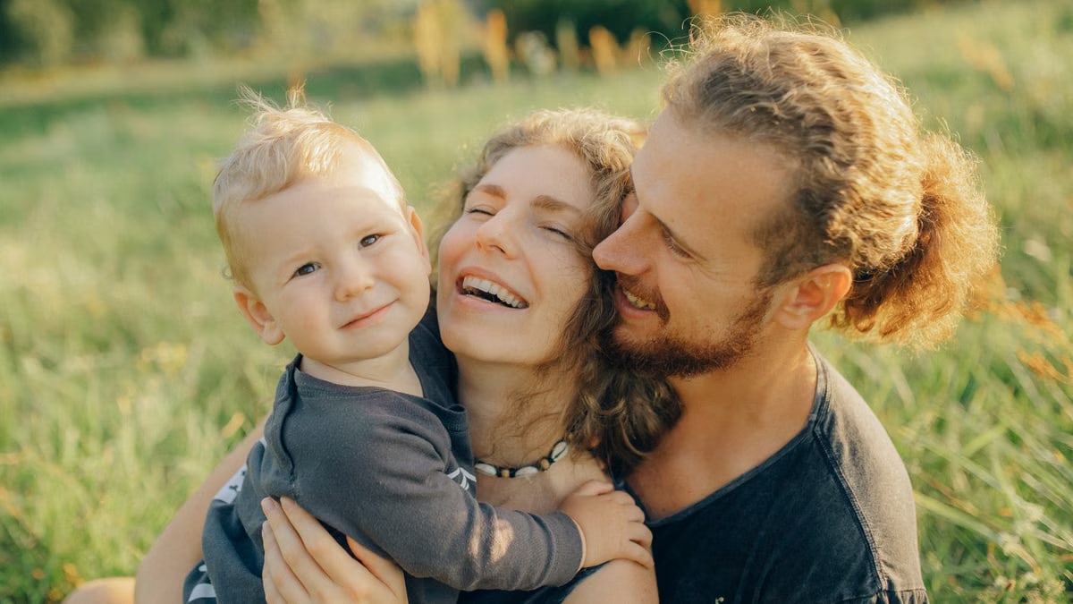 A joyful family moment captured in a sunny meadow, portraying love and togetherness.